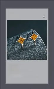 Détail de boucles d'oreilles étoiles bicolores or et argent sur cuir bleu marine