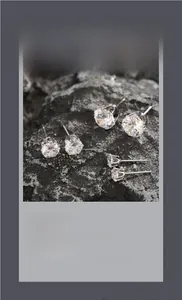 Detailed view of three pairs of silver four-prong round-cut zircon stud earrings set