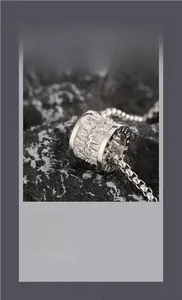 Macro shot of silver cylindrical pendant with zircon stones and LOVED engraving