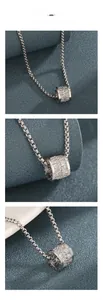 Macro detail of silver cylinder pendant with cubic zirconia inlay on a metal box chain