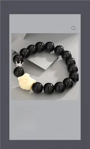 Detailed macro view of black obsidian beads with white floral and silver crown charms