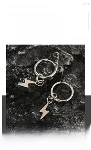 Gros plan de boucles d'oreilles éclair en acier titane argent sur pierre noire