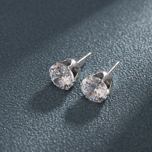 Classic six-claw silver earrings with round cubic zirconia on navy leather background