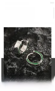 Macro detail of titanium steel avocado hoop earrings with green enamel and hollow heart patterns