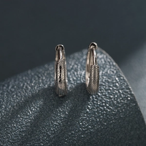 Boucles d'oreilles créoles argentées avec surface métallique texturée style industriel