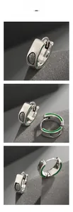 Macro detail of silver hoop earrings with green enamel coating and black grid patterns