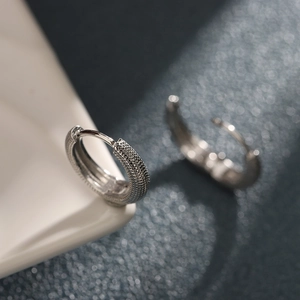 Créoles en argent avec texture pointillée sur bord de céramique blanche vue macro