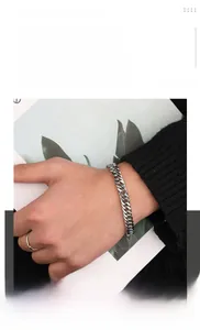 Close-up of a polished titanium steel Cuban link bracelet on a wrist in silver finish