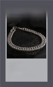 Close-up of a silver Cuban link bracelet on a black rock surface showing high gloss finish