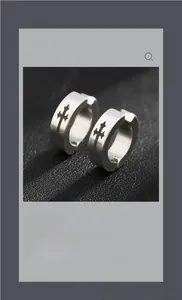 Détail macro de boucles d'oreilles créoles en acier argenté mat avec croix noires gravées