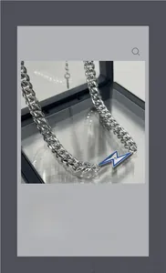 Détail du collier chaîne cubaine en acier titane avec pendentif éclair en émail bleu