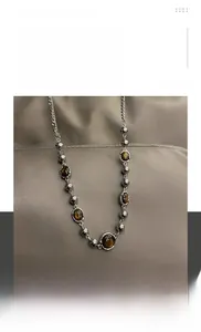 Vue macro des perles en acier titane et du pendentif œil de tigre d'un collier hip-hop