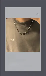 Gros plan sur collier en œil de tigre et perles argentées sur un sweat gris neutre