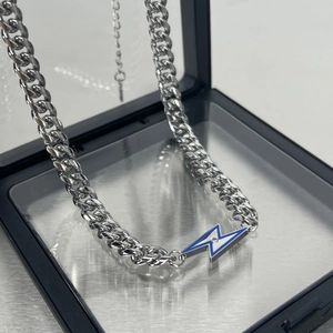 Collier avec pendentif éclair en acier titane et chaîne cubaine sur boîte à bijoux