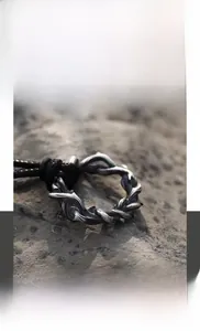 Vue détaillée du pendentif épines en acier titane avec cordon noir sur pierre naturelle