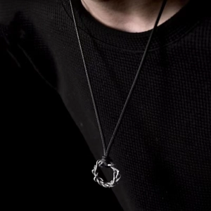 Collier minimaliste à pendentif épine en argent avec cordon cuir noir porté sur un pull