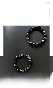 Gros plan du bracelet en obsidienne avec breloque tête de lion en argent et perle dorée