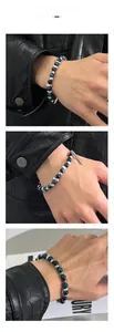 Close-up of blue tiger eye natural stone beads and silver metal tube pendant on a bracelet