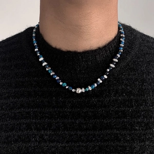 Collier de perles bleues avec accents argentés sur un pull en maille noir