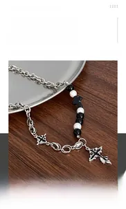Detail of hip hop cross necklace featuring black beads and white faux pearls in titanium steel
