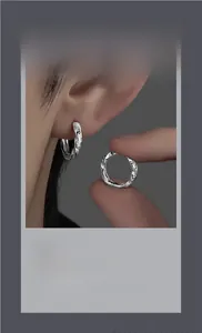 Détail des boucles d'oreilles créoles Mobius argentées avec texture torsadée et gravure