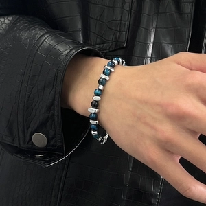 Blue tiger eye beaded bracelet with silver metal beads on a man's wrist over leather