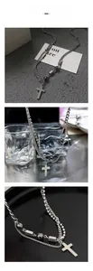 Détail du collier croix à deux couches avec chaînes argentées et pièces hexagonales