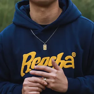 Ensemble collier avec pendentif montagne en acier titane et bague gravée sur sweat bleu
