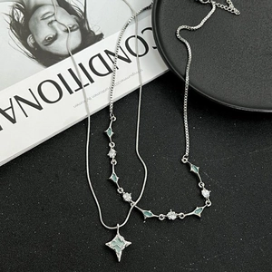 Silver double-layer star necklace with green zircon pendants on black textured background