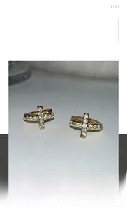 Gros plan de boucles d'oreilles croix dorées serties de cristaux de style hip hop