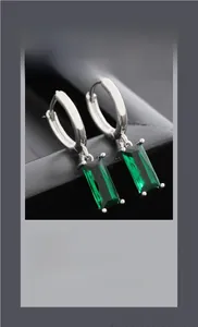 Macro shot of emerald green rectangular gemstone drop earrings with silver hoop setting