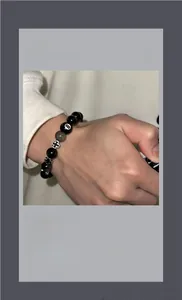 Gros plan du bracelet en obsidienne avec croix argentée et motif boule de billard n°8