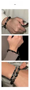 Détail du bracelet en perles d'obsidienne avec boule numéro 8 et charmes de croix