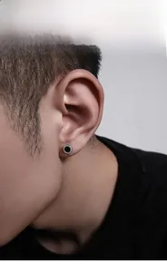 Macro shot of men's round earring featuring a black glossy center and studded silver frame