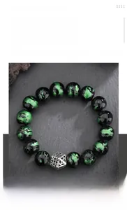 Macro detail of green seraphinite beads bracelet with silver geometric spacer on rock