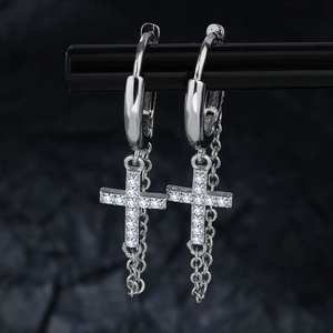 Silberne Kreuz-Ohrringe mit Zirkoniasteinen und Kettenquasten auf dunklem Felsuntergrund