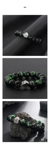 Close-up of green seraphinite beads bracelet with silver hollow metal charm on black rock