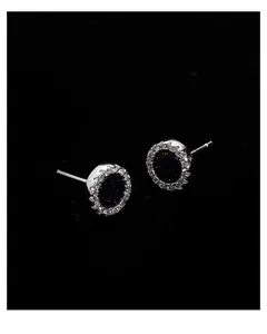 Macro detail of silver cluster earrings with black starry inlay and pavé zircon border