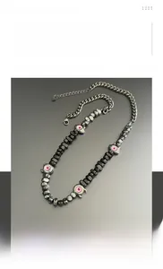 Detalle del collar de acero de titanio con cuentas irregulares y colgantes de ojo rosa