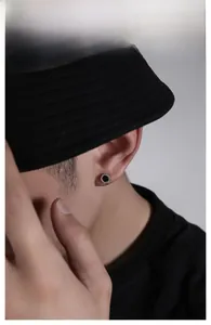 Close-up of a men's round black stud earring with sparkling micro-pave crystals