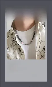 Detalle del collar de cuentas gris oscuro con colgantes de ojos en el cuello