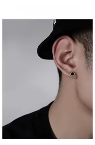 Macro shot of men's black round stud earring with white zircon inlay on male model