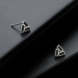 Dettaglio macro di orecchini a triangolo in argento geometrico con smalto nero lucido