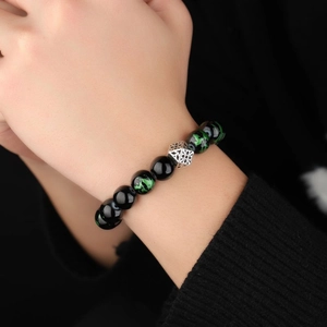 Seraphinite beaded bracelet with silver geometric charm worn on a male wrist