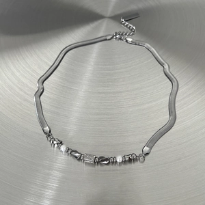 Minimalistische silberne Schlangenkette mit Perlen und Metallperlen auf Metallhintergrund