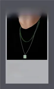 Close-up of double-layer necklace with green curb chain and checkered enamel pendant