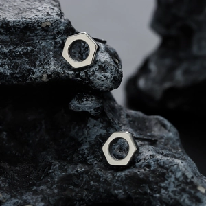 Industrial hex nut stud earrings in silver finish on black volcanic rock texture