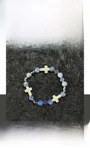 Détail d'un bracelet en perles bleues texturées avec pendentif croix et accents argentés
