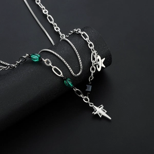 Collier multicouche argenté avec perles vertes et pendentif étoile sur socle noir