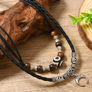 Retro woven necklace with dark wood beads and silver crescent pendant on wood background